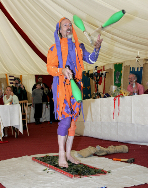 Kris Katchit, jester, juggling while walking over a bed of broken glass.